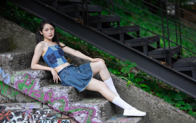 Девушка азиатка в юбке лежит на лестнице