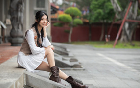 Азиатка сидит на холодных ступеньках