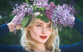 Красивая голубоглазая девушка с венком из сирени на голове