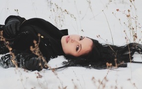 Красивая брюнетка лежит на холодном снегу
