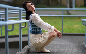 Милая девушка азиатка сидит у перил