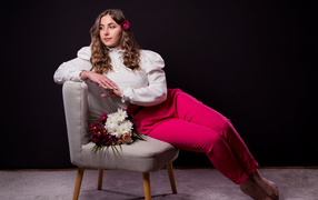 Милая девушка сидит на сером кресле с цветами