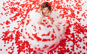 Девушка в белом платье сидит на лепестках розы