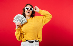 Девушка с веером из долларов на красном фоне