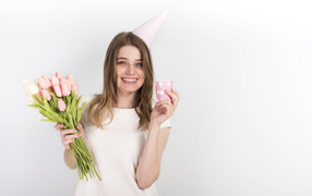 Счастливая девушка с букетом тюльпанов и подарком на день рождения