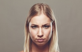 Серьезная девушка с короткой стрижкой на сером фоне