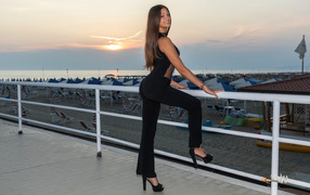 Улыбающаяся девушка стоит у перил 