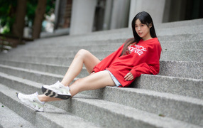 Молодая азиатка в кроссовках лежит на лестнице