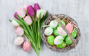 Basket of colorful Easter eggs with a bouquet of tulips
