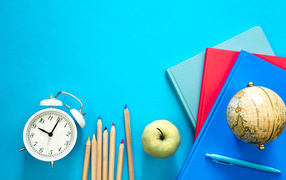 Books on the table with a globe, pencils and alarm clock