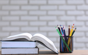 Разноцветные карандаши на столе с книгами 