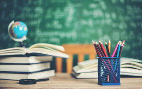 Карандаши на столе с книгами в школьном классе