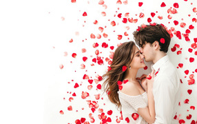 Красивая влюбленная пара в лепестках роз на белом фоне