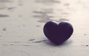 Черное каменное сердце на деревянной поверхности 