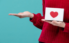 Коробка с сердцем в руке у девушки на голубом фоне