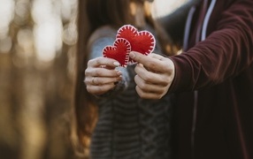 Влюбленная пара держит сердечки в руках