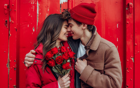 Влюбленная пара с букетом красных роз у стены