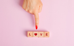 Рука указывает на кубики с надписью любовь на розовом фоне