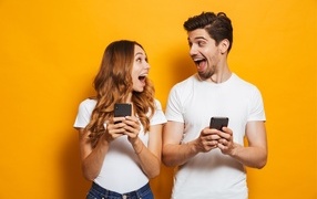 Счастливые парень и девушка с мобильными телефонами