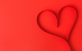 Сердце из атласной ленты на красном фоне