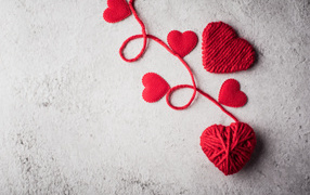 Сердечки из красной шерстяной нити на сером фоне
