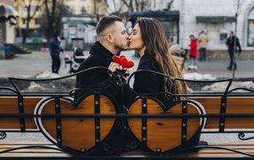 Поцелуй влюбленной пары на лавке в парке