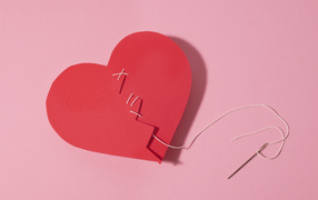 Бумажное сердце сшили нитками на розовом фоне