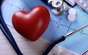Красное сердце на столе с кардиограммой и стетоскопом