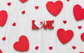 Надпись любовь с красным сердечками на деревянном фоне