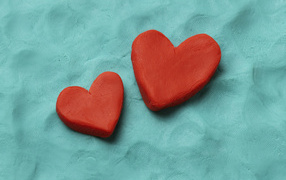 Два красных сердца из пластилина на голубом фоне