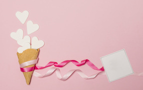 Вафельный рожок с сердечками, лентами и листом бумаги на розовом фоне