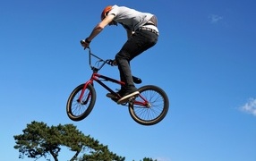 Мужчина делает прыжок на велосипеде на фоне неба
