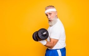 Спортивный мужчина с гантелей в руке на желтом фоне