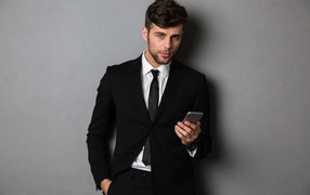 Деловой мужчина в костюме стоит у стены с телефоном