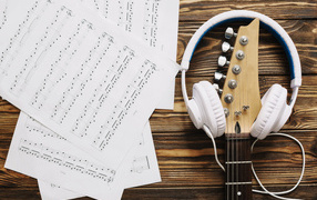 Ноты, наушники и гитара на столе