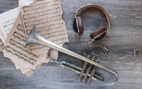 Старые ноты, наушники и труба на столе