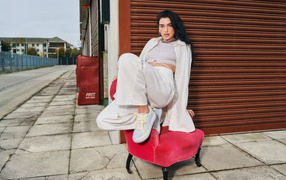 Певица Дуа Липа в белом костюме на кресле у стены