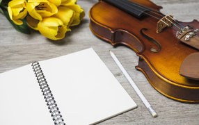 Скрипка, блокнот и желтые тюльпаны на столе
