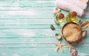 Соль, масла и полотенце с ракушками на голубом фоне для спа