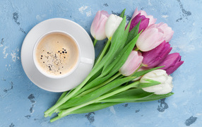 Букет разноцветных тюльпанов с чашкой кофе на голубом столе