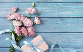 Букет розовой эустомы с подарком на голубом фоне