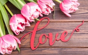 Букет розовых тюльпанов с надписью любовь на деревянном столе