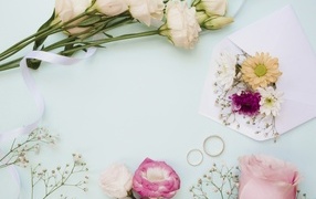 Цветы на голубом фоне с конвертом и обручальными кольцами