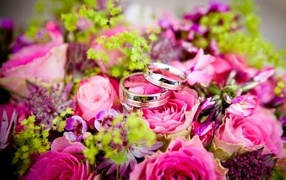 Два обручальных кольцо на букете розовых цветов