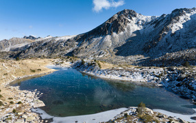 Ice-covered lake in snow-capped mountains in the sun, Andorra