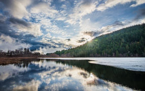 Рассвет яркого солнца над лесом у озера