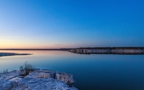 View of a beautiful calm river under a blue sky at dusk