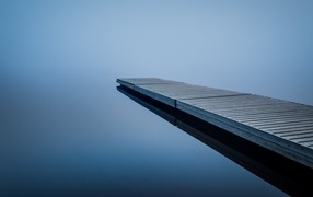 Wooden bridge near a lake in the fog
