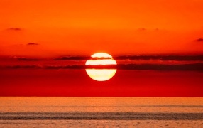 Яркое солнце в облаках на закате над морем 