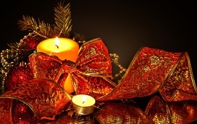 Зажженная свеча с красным бантом на черном фоне на Новый год